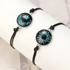 Detailaufnahme der leuchtenden Sonne und Mond Anhänger an schwarzen geflochtenen Armbändern