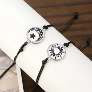 Detailaufnahme der gewebten schwarzen Armbänder mit leuchtenden Sonnen- und Mondanhängern
