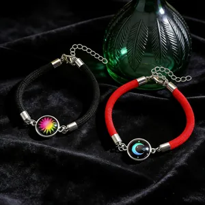 Detail von handgewebten Sonnen- und Mond-Armbändern mit leuchtenden Glasanhängern auf Samt