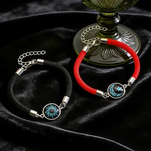 Detailaufnahme von leuchtenden Sonnen- und Mondanhängern an geflochtenen Armbändern
