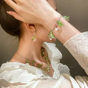 Detalle del conjunto de joyas de frutas rosas con collar y pendientes en modelo