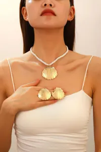 Detail view of beach style gold starfish earrings and seashell necklace on model