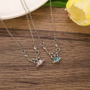 Dettaglio dei ciondoli pianeta cuore rosa e blu con fiocchi su catena in argento