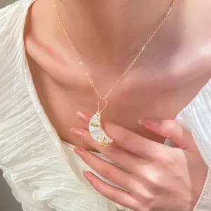 Detalle de un collar con colgante de luna creciente en nácar usado por una modelo real