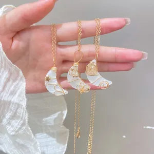 Collar dorado artesanal con colgante de luna creciente y detalles de estrellas y lazos