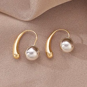 Detail of two-tone elegant metal droplet earrings on a brown silk textured background