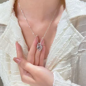 Silver necklace with double heart pendant featuring a purple stone on a woman's neck