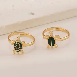 Set di anelli dorati a forma di tartaruga con trama a nido d'ape verde su marmo