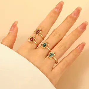Set di quattro anelli a tartaruga dorati con gusci in smalto colorato su mano