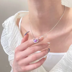 Detail van de zilveren hartketting met paars kristal en witte diamanten op het model