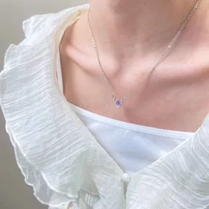 Detailopname van een maan en zon hanger ketting met paarse edelsteen op een model