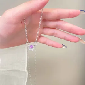 Detailweergave van zilveren zonne-hanger met roze edelsteen en witte strassteentjes