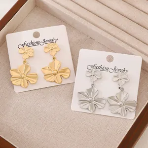 Detalle de pendientes de flores dorados y plateados con diseño de doble flor en tarjeta