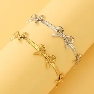Nahaufnahme von Schlangenarmbändern in Gold und Silber mit Schleifenanhängern auf Stativ
