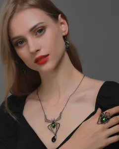 Gothic spider jewelry set featuring green crystals on dark metal worn by a model