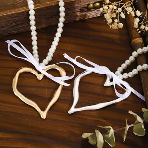 Détails de grands pendentifs en forme de cœur avec nœuds blancs et colliers de perles