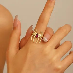 Detailed view of a gold spider ring featuring a ruby-red marquise gemstone on a finger