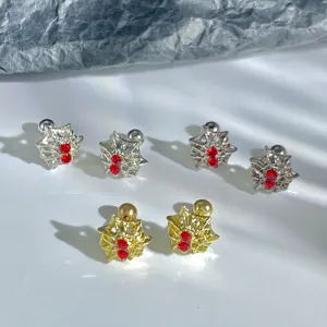 Macro detail of star-shaped stud earrings in gold and silver finish with red crystals