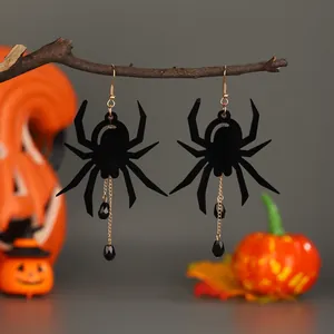 Gothic spider earrings with black tassels and gold hooks on autumn branches background