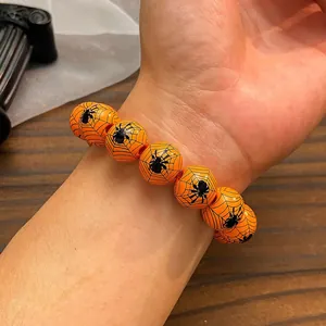 Gros plan du bracelet d'Halloween perlé orange avec motifs de toiles d'araignées noires