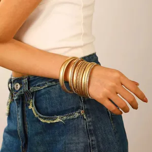 Detail of stacked gold bangles with textured patterns and sparkling rhinestones on wrist