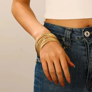 Close-up of stacked gold alloy bangles with smooth and textured glitter finishes