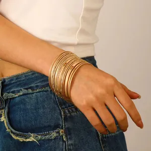 Detailed view of stacked thin gold bangles with smooth and textured finishes on wrist