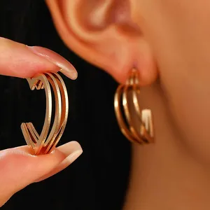 Detailed view of triple-layered golden heart hoop earrings with brushed metal finish