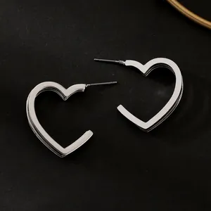 Detailed view of polished silver heart-shaped hoop earrings on a dark background