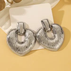 Detail of silver heart earrings featuring a vintage brushed metal texture on stone stand