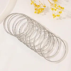 Detailed view of silver stacking bangles with smooth and spiral textured finish on satin fabric