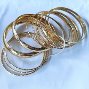 Detail showing stacked golden alloy bracelets with engraved patterns and small rhinestones