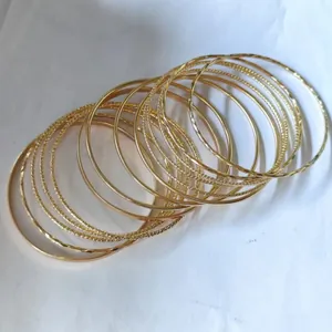 Detailed view of stacked gold bangles featuring smooth, spiral, and embossed textures