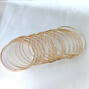 Close-up of 15-piece set gold alloy bangles with smooth and spiral textured finish