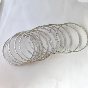 Close-up of stacked silver bangles featuring smooth finish and twisted rope textures