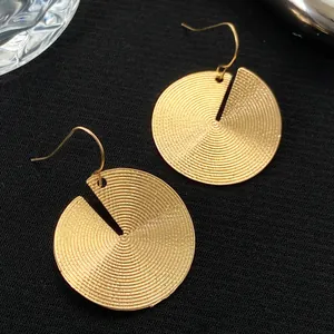 Golden disc hook earrings with spiral texture and unique wedge-shaped cutouts