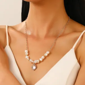 Primer plano del collar de perlas con colgante de flor dorada sobre un vestido de seda
