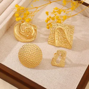 Detail of four chunky gold punk rings featuring hammered texture and geometric hollow shapes