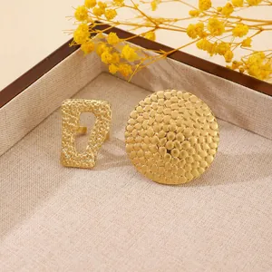 Detail of two gold-toned chunky rings with hammered texture and hollow geometric design