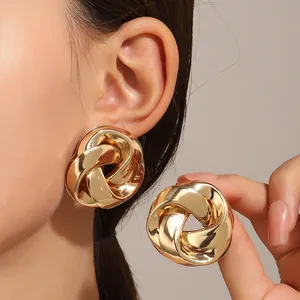 Close-up of elegant large golden twist stud earrings worn for a stylish daily look