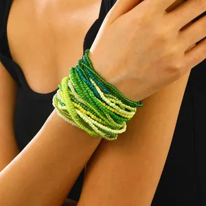 Detail of layered gradient green and yellow seed bead elastic bracelet set on wrist