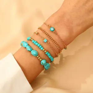Detail of five-piece gold and turquoise beaded bracelet set with evil eye charm on wrist