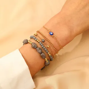 Detailed view of 5-piece gold and grey bead bracelet set with blue evil eye charm