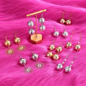 Orecchini a sfera disco in oro e argento su un vivace sfondo di peluche rosa acceso