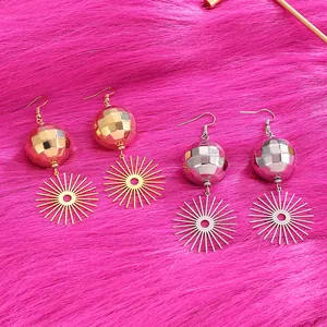 Dettaglio degli orecchini a sfera disco oro e argento su tessuto di peluche rosa