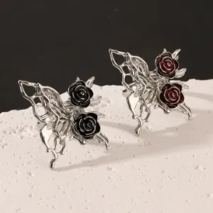Close-up of gothic silver butterfly wings and rose earrings with black and red enamel details