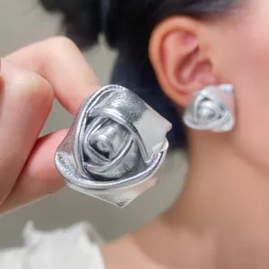 Detail of silver 3D rose stud earrings with metallic PU leather texture and petal folds