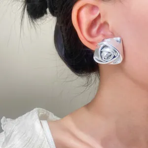 Close-up of a model wearing a silver 3D rose flower stud earring made of PU leather