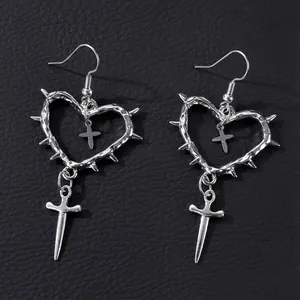 Macro shot of silver gothic heart earrings with thorns and cross charms on leather