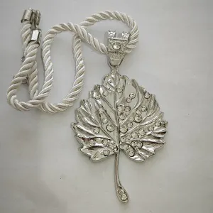 Detailed macro view of silver leaf pendant with white rhinestones and braided cord